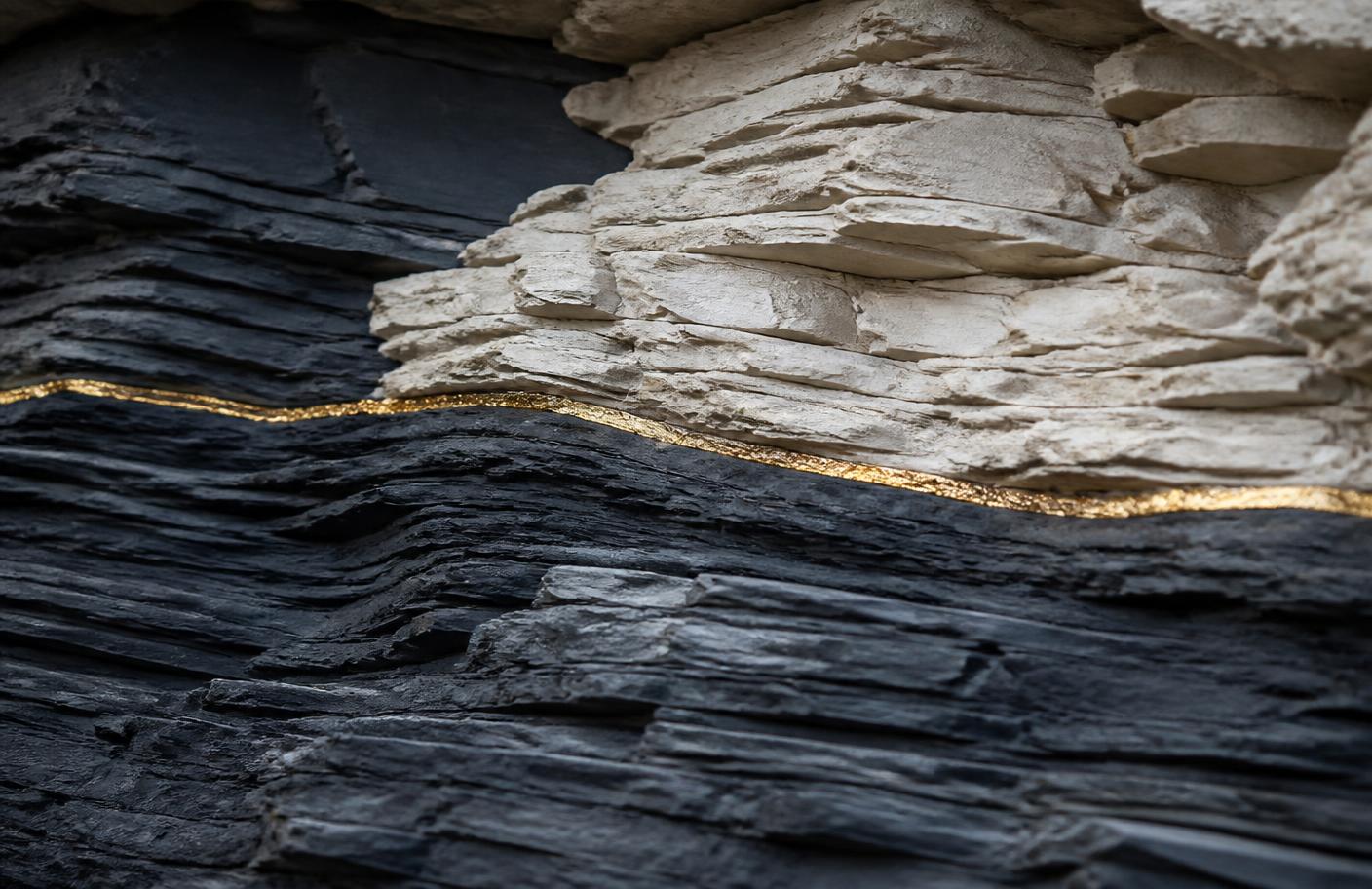 Layered navy slate and pale limestone strata divided by a single thin gold seam